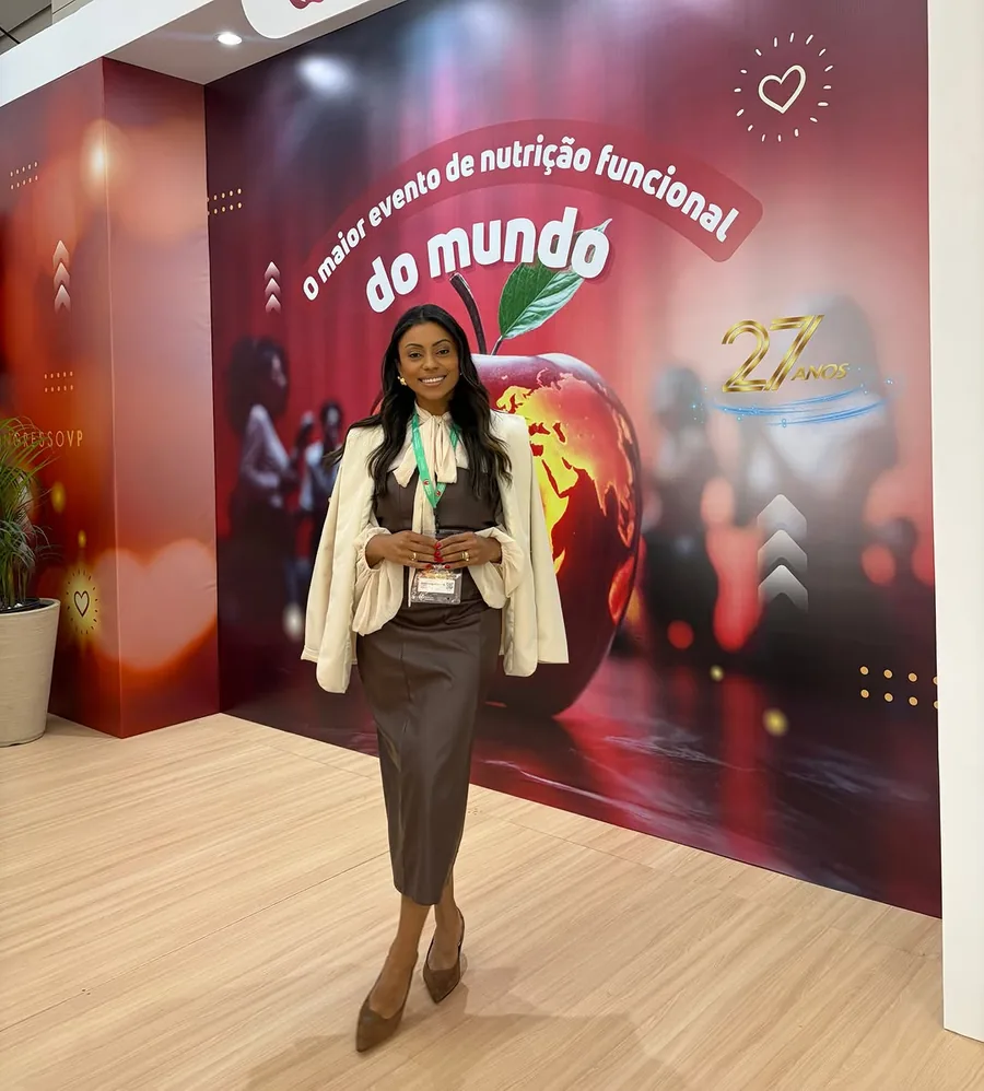 Mariana no Congresso Internacional de Nutrição Funcional, em frente ao painel do evento