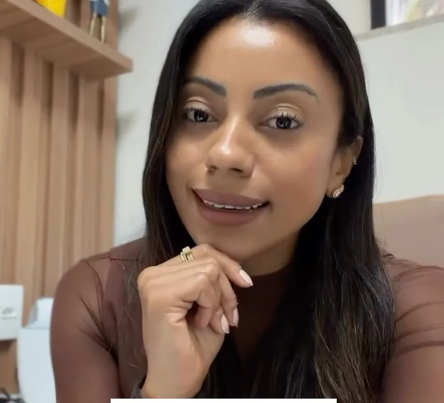 Mariana Quintanilha no consultório, com a mão no queixo, diante de prateleiras de madeira
